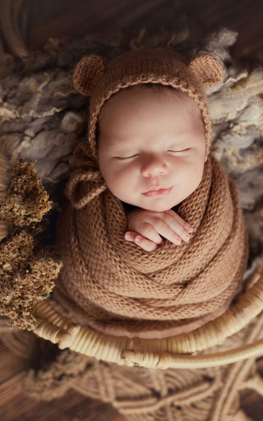 baby in gray sweater lying on white textile